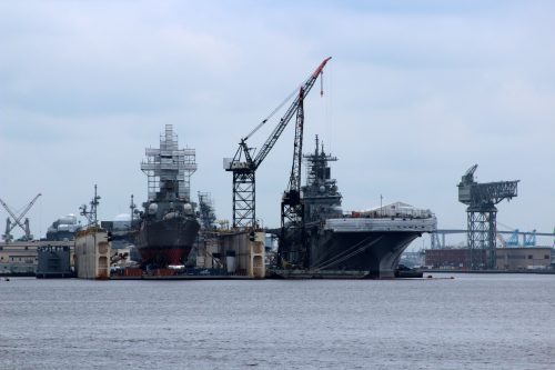 Navy ships in dry dock with a large crane at a shipyard