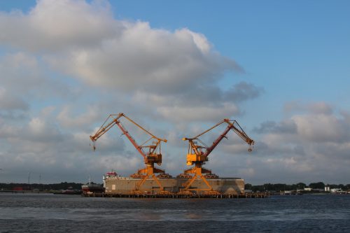 Twin harbor cranes standing over a floating dry dock at sunset