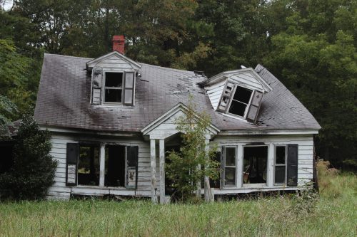 Abandoned farmhouse with a collapsed dormer and brick chimney