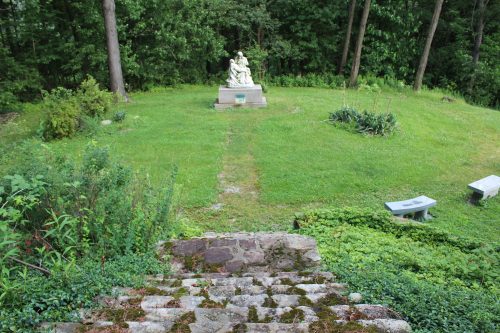 Stone steps leading to a religious statue in a wooded garden