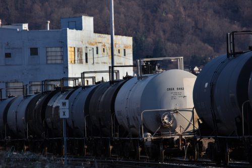 Row of railroad tank cars beside an old brick building